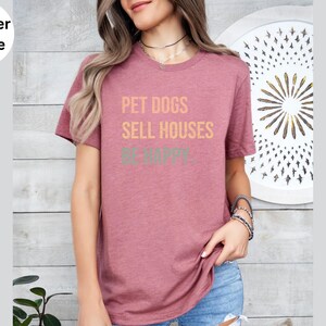 a woman wearing a realtor t - shirt that says pet dogs sell houses be happy