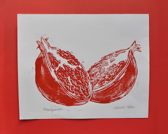 May include: Red and white linocut print of two pomegranate halves. The print is signed "Pomegranate" and "Catherine Wake".