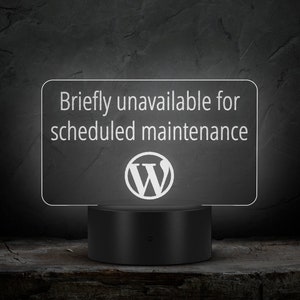 May include: A white sign with the text "Briefly unavailable for scheduled maintenance" and the WordPress logo. The sign is lit up and sitting on a black base.