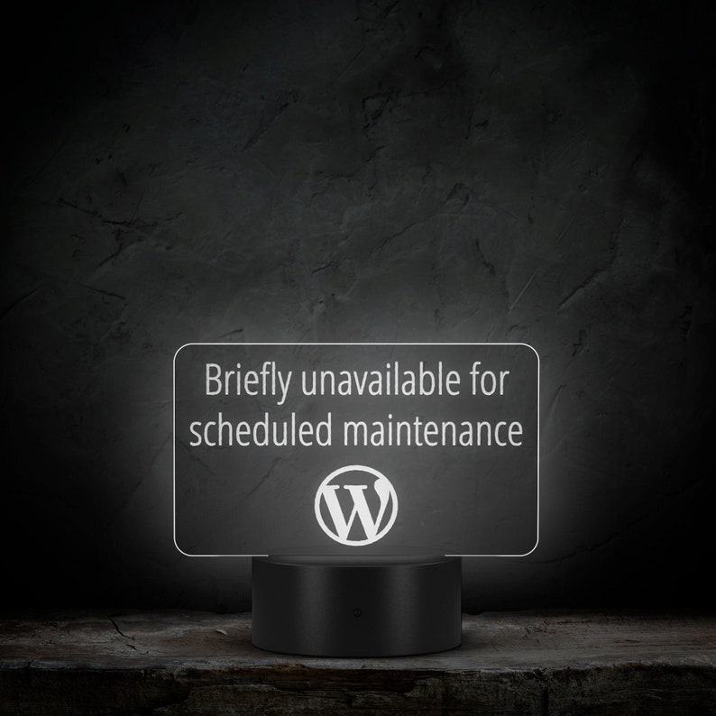 May include: A white sign with the text "Briefly unavailable for scheduled maintenance" and the WordPress logo. The sign is lit up and sitting on a black base.