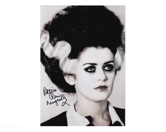 Puede incluir: Retrato en blanco y negro de una mujer al estilo de la Novia de Frankenstein. Presenta un maquillaje dramático, labios oscuros y una firma. Su cabello está peinado con el icónico estilo blanco y negro.