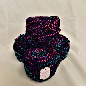 May include: Three skeins of yarn in a black, purple, and teal color combination. The yarn is wound into balls and has a tag that reads "100% Merino 4 oz."
