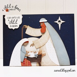 May include: A Christmas card kit with a blue background and a white, red, and brown paper cut-out of the nativity scene. The text "For unto us a child is born" is on the card.