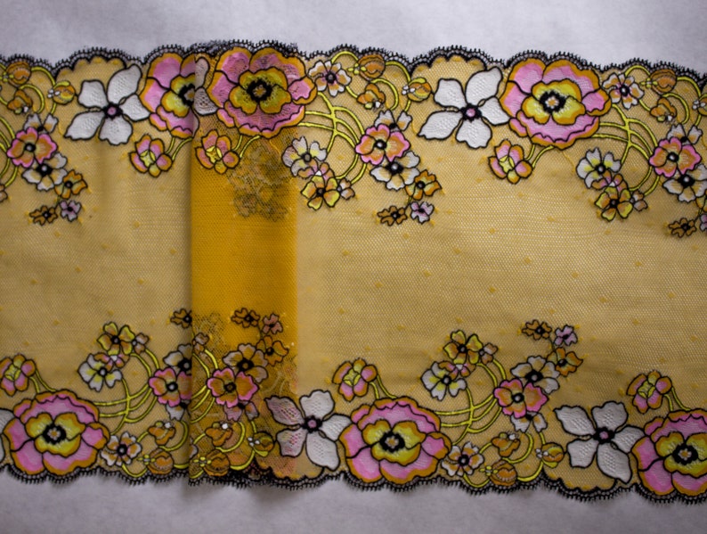K&ouml;nnte beinhalten: Gelber floraler Spitzenbesatz mit schwarzen und wei&szlig;en Bl&uuml;ten und rosa Akzenten. Die Spitze hat ein zartes, vintage-inspiriertes Design.