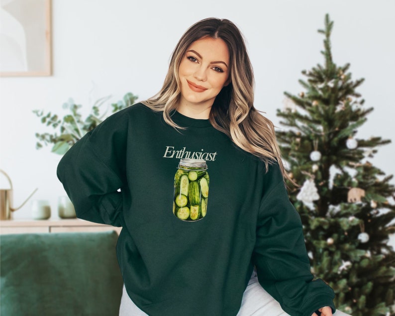 Op de afbeelding: Een donkergroen sweatshirt met de tekst "Enthusiast" en een afbeelding van een pot vol groene augurken.