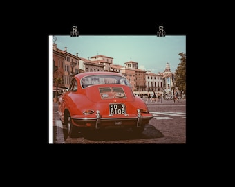 May include: A red vintage Porsche 911 driving through a European city street. The car has a license plate that reads "SO 3 8108".