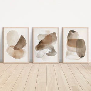 Puede incluir: Tres pinturas abstractas de acuarela enmarcadas con formas marrones y beige sobre un fondo blanco.