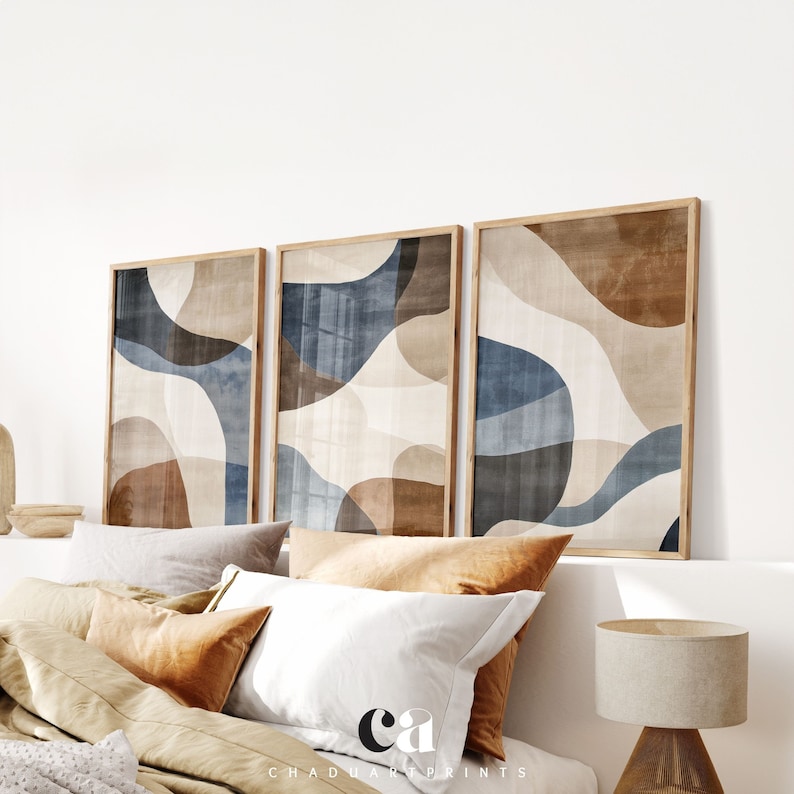 Pode incluir: Tr&ecirc;s impress&otilde;es de arte abstrata em molduras de madeira castanho. As impress&otilde;es apresentam um design moderno com formas sobrepostas em tons de azul, castanho e bege.