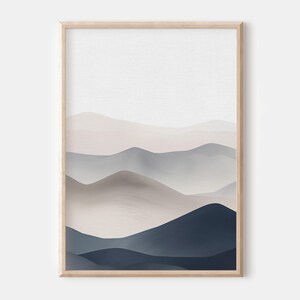Puede incluir: Impresi&oacute;n de arte abstracto con un paisaje minimalista de monta&ntilde;as superpuestas en capas en tonos de azul, gris y beige. La impresi&oacute;n est&aacute; enmarcada en un marco de madera claro.
