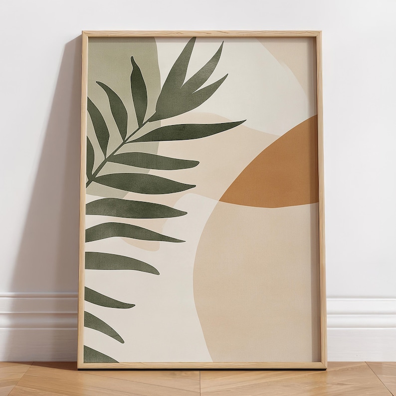 May include: Abstract art print with a green leaf and beige, brown, and orange shapes. The print is framed in a light wood frame.