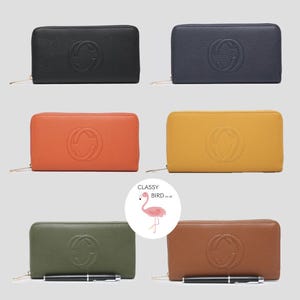 May include: Six different coloured leather wallets with a gold zipper and an embossed double G logo. The wallets are arranged in two rows of three. The wallets are black, navy blue, orange, yellow, green, and brown.