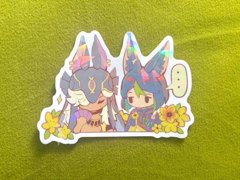May include: A holographic sticker featuring two anime-style characters with animal ears and floral accents. One character holds a fan, and the other has a speech bubble. The sticker has a white border and is set against a green background.