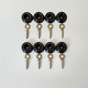 May include: A set of eight black rubber furniture feet with screws and washers. The feet are designed to protect floors from scratches and provide stability.