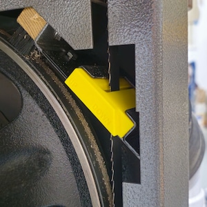 May include: Close-up of a black band saw with a yellow plastic blade guard. The saw blade is visible in the center of the image.