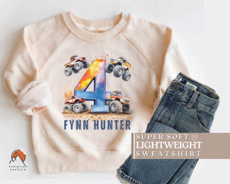 May include: A light beige sweatshirt with a colorful number four and monster truck graphic. The text "Fynn Hunter" is printed below the graphic. The text "SUPER SOFT LIGHTWEIGHT SWEATSHIRT" is printed on a separate piece of fabric.