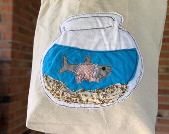 Bolso de mano único con forma de tiburón, elaborado con materiales reciclados.