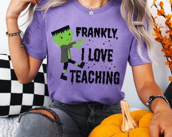 Könnte beinhalten: Ein lila T-Shirt mit dem Text "FRANKLY, I LOVE TEACHING" und einer Cartoon-Figur von Frankenstein. Das Monster ist grün mit schwarzen Haaren und trägt eine graue Jacke und eine schwarze Hose. Das Shirt hat einen Rundhalsausschnitt.