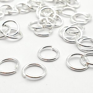 May include: A pile of silver jump rings, a type of jewellery finding used for connecting chains, cords, and other jewellery components.