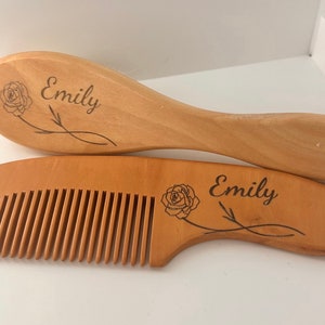 May include: A wooden hairbrush and comb set with the name "Emily" engraved on each piece. Both pieces feature a rose design.