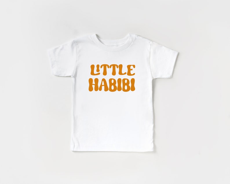 May include: White short-sleeved t-shirt with the text "LITTLE HABIBI" in orange.