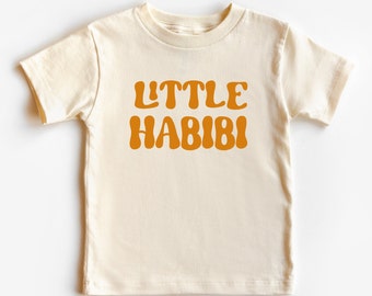 May include: A cream colored short-sleeved t-shirt with the text "LITTLE HABIBI" in orange.