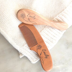 May include: A set of two wooden hair combs with the name "Emily" engraved on each comb. The combs are decorated with a rose design.