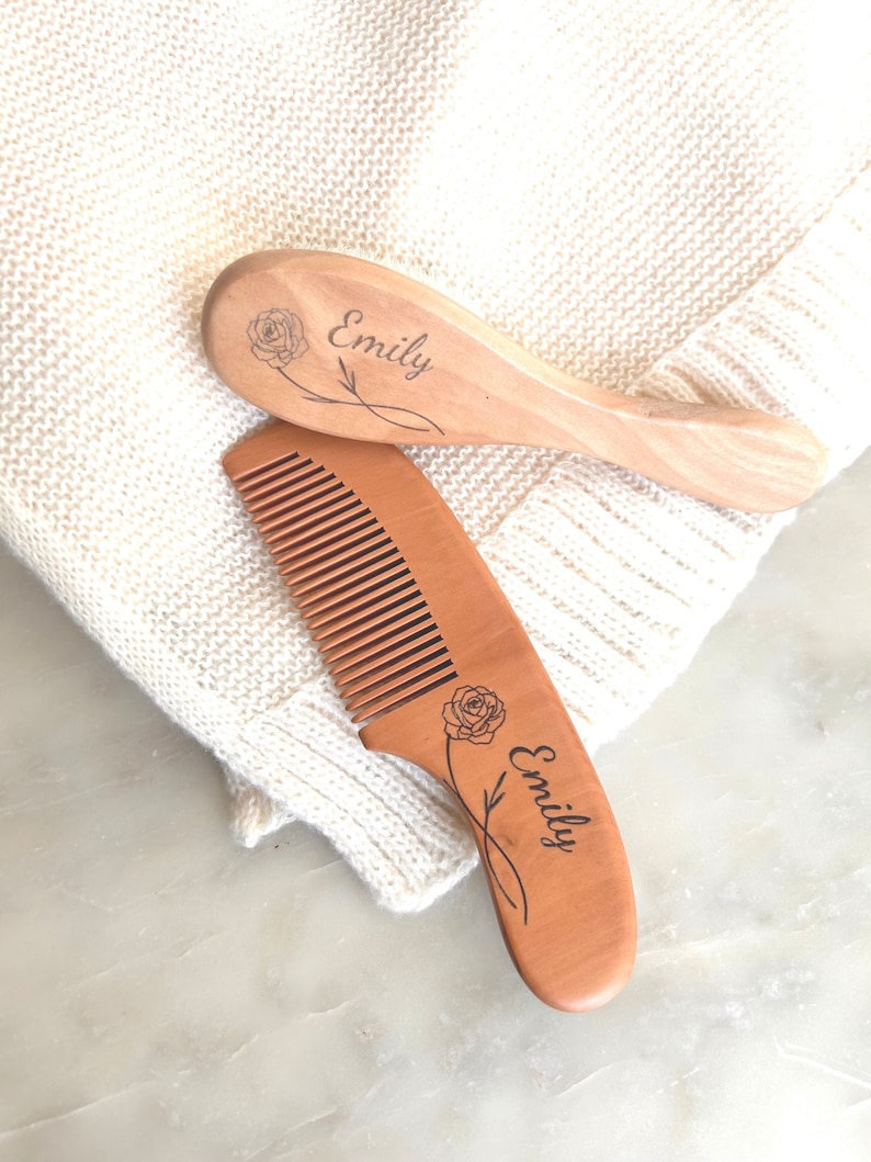 May include: A set of two wooden hair combs with the name "Emily" engraved on each comb. The combs are decorated with a rose design.