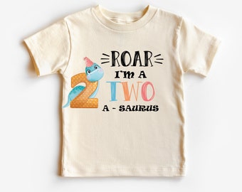 May include: A cream colored t-shirt with a blue dinosaur wearing a party hat. The shirt has the text "Roar I'm a Two-saurus" printed on it.