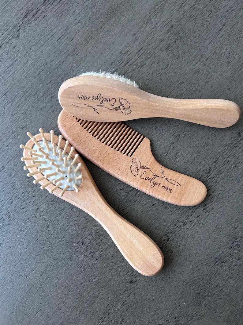 May include: Three wooden hair brushes with personalized names. The brushes are made of natural wood and have a soft bristle design. The names are "Evelyn Rose", "Evelyn Rose", and "Cozier Rose".
