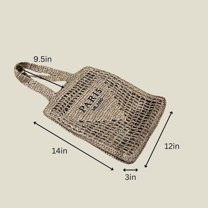 May include: Woven beige tote bag with the text "PARIS MILANO". The bag measures 14 inches long, 12 inches wide, and 3 inches deep, with a handle that is 9.5 inches long. The bag is made of a woven material.