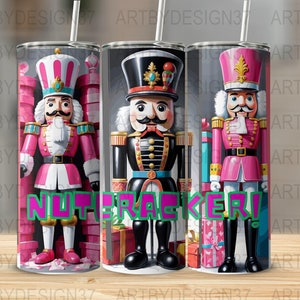 May include: Three stainless steel tumblers with a Christmas nutcracker theme. The tumblers feature different nutcracker designs, including a pink nutcracker, a black and gold nutcracker, and a pink and gold nutcracker. The tumblers are all decorated with Christmas-themed elements, such as presents and candy canes. The text "NUTCRACKER!" is printed in green and pink letters on the tumblers.