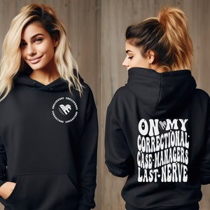 May include: Black hoodie with a white heart design on the front and the text "ON MY CORRECTIONAL CASE-MANAGERS LAST NERVE" on the back.