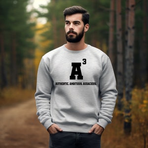 May include: A gray sweatshirt with a black graphic of the letter "A" with a superscript "3" and the text "AUTHENTIC. AMBITIOUS. AUDACIOUS."