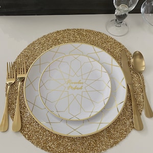 May include: A gold glitter placemat with a white plate featuring a gold geometric pattern and the text "Ramadan Mubarak".