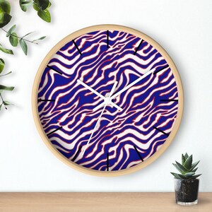 May include: A round wall clock with a white, blue and red zebra-like pattern. The clock has black hour markers and white hands.