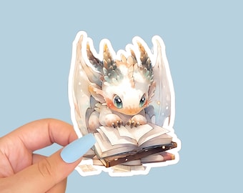 May include: A white dragon with blue eyes is reading a book. The dragon is sitting on a stack of books. The dragon has a light blue and green design on its back.