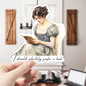 May include: A sticker featuring a vintage illustration of a woman reading a book. The text on the sticker reads "I should infinitely prefer a book."