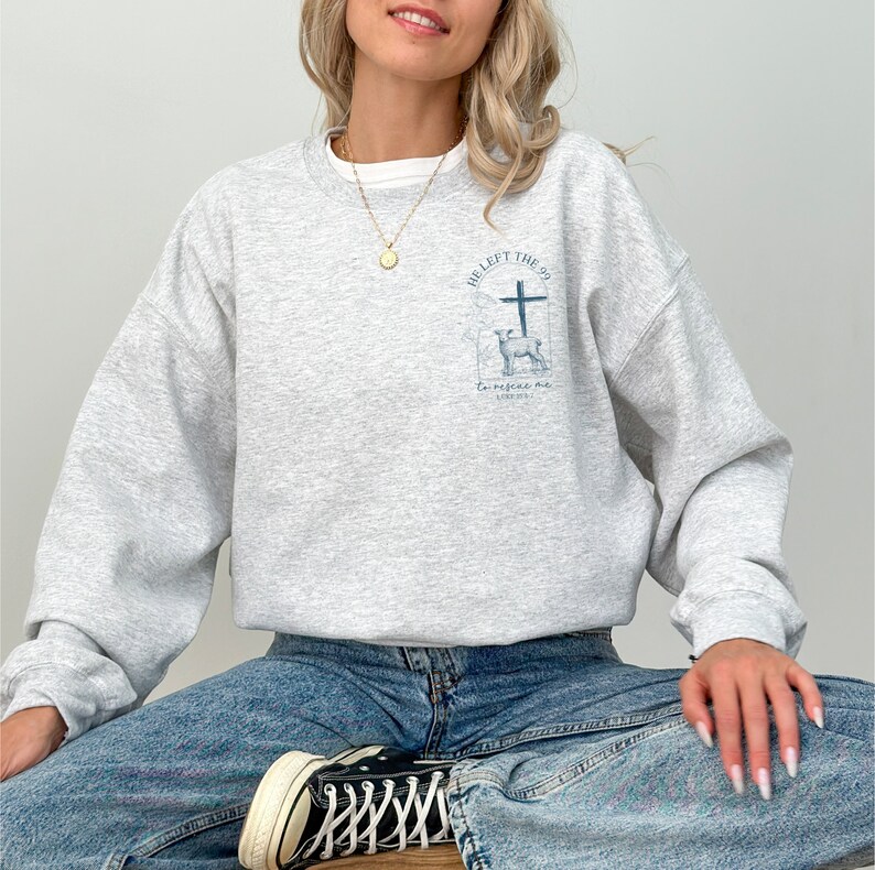 Pu&ograve; includere: Una felpa grigia con una stampa grafica di una croce e un cervo. Il testo sulla grafica recita "He left the 99 to rescue me Luke 19:10".
