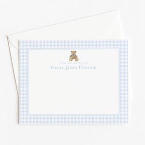 May include: A stationery set with a light blue gingham pattern and a teddy bear illustration. The card reads "From the nursery of Henry James Peterson" in a delicate font, with a matching envelope.