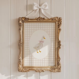 May include: A framed print of a watercolor illustration of a white duck with a pink bow on a gingham background.