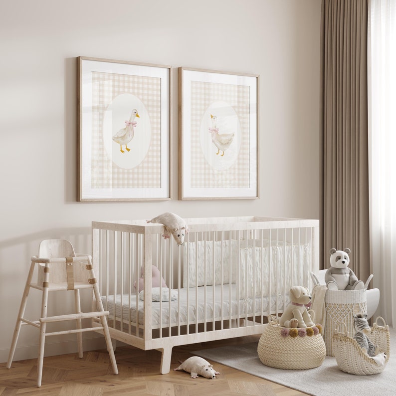 May include: A white crib with a white mattress and a white wooden high chair. There are two framed prints of a duck with a pink bow on a pink and white gingham background. There are also several stuffed animals, including a panda, a dog, and a rat.