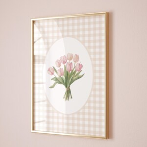 Pu&ograve; includere: Una stampa incorniciata con un'illustrazione ad acquerello di un mazzo di tulipani rosa su sfondo bianco con un bordo a quadri marroni e bianchi.