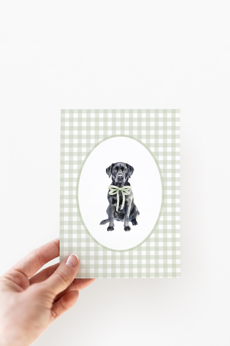 May include: A black Labrador Retriever wearing a light green bow tie sits in a white oval frame against a green and white gingham background.