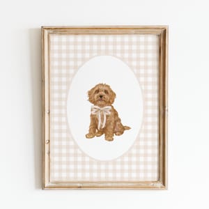 Op de afbeelding: Een ingelijst afdruk van een bruine hond met een witte strik die in een ovaal op een beige en witte ruitjesachtergrond zit.