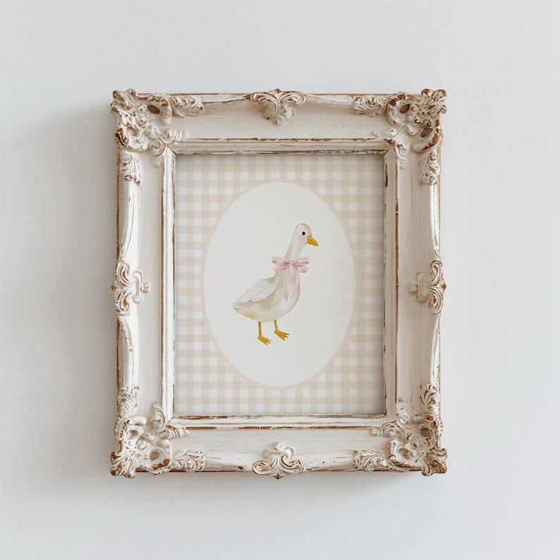 May include: A white framed print with a gingham background and a white duck with a pink bow in a circular frame.