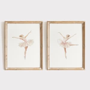 May include: Two framed watercolor paintings of ballerinas in pink tutus. The ballerinas are posed in mid-air with their arms outstretched.