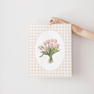 Pu&ograve; includere: Una stampa d'arte stampabile con un bouquet di tulipani rosa in una cornice ovale bianca su uno sfondo a quadri vichy beige e bianco.