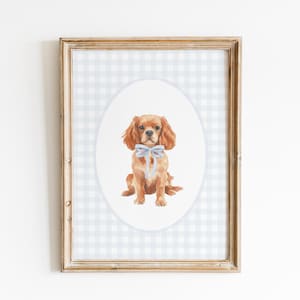 Könnte beinhalten: Gerahmter Aquarelldruck mit einem Cavalier King Charles Spaniel mit hellblauer Schleife. Der Hund ist auf einem weißen Oval vor einem hellblau-weiß karierten Hintergrund zentriert. Der Rahmen ist hellbraun.