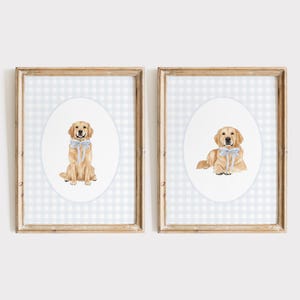 Può includere: Due stampe incorniciate con illustrazioni ad acquerello di Golden Retriever. Una mostra un cane seduto, l'altra un cane sdraiato, ognuno con un fiocco blu. Lo sfondo è un motivo a quadretti vichy blu chiaro e bianco.