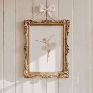 May include: A gold-framed print of a ballerina in a white tutu and pink leotard, with a white satin ribbon bow hanging above the frame.
